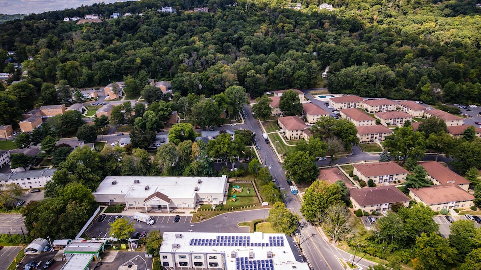A residential area with houses, a parking lot, and solar panels on a building.