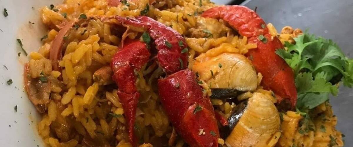 A plate of seafood paella with red peppers and mussels.
