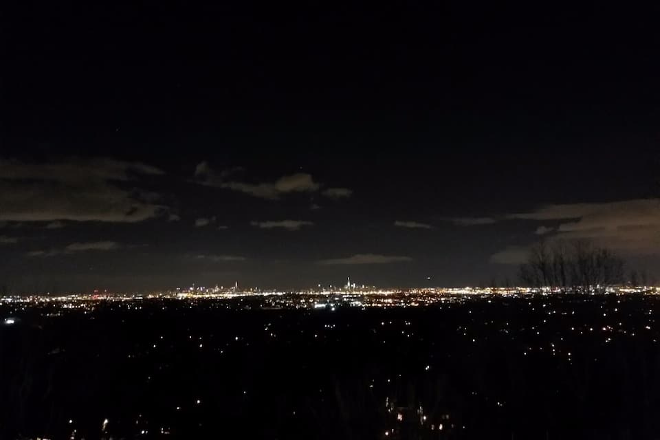 A nighttime cityscape with a prominent skyline and distant lights.