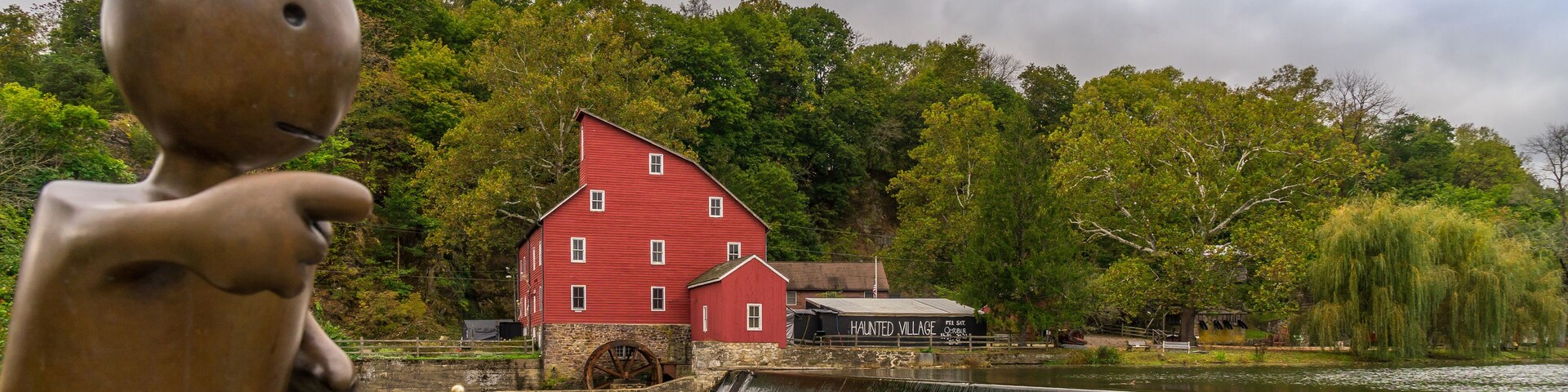 The historic Red Mill in Clinton NJ with bronze sculpture of little boy in foreground