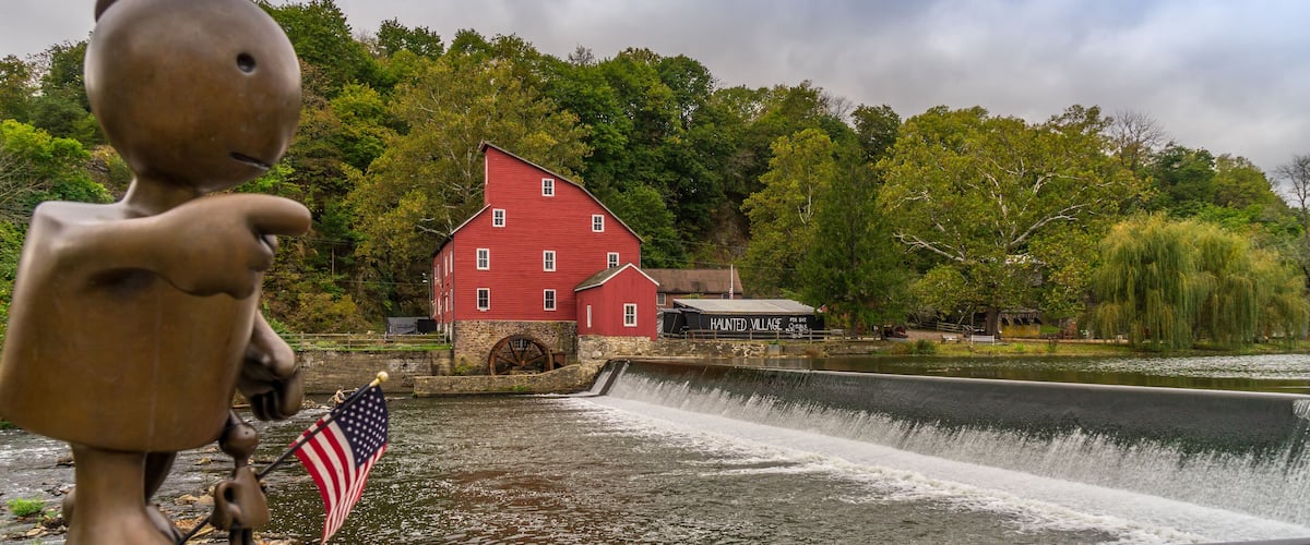 The historic Red Mill in Clinton NJ with bronze sculpture of little boy in foreground