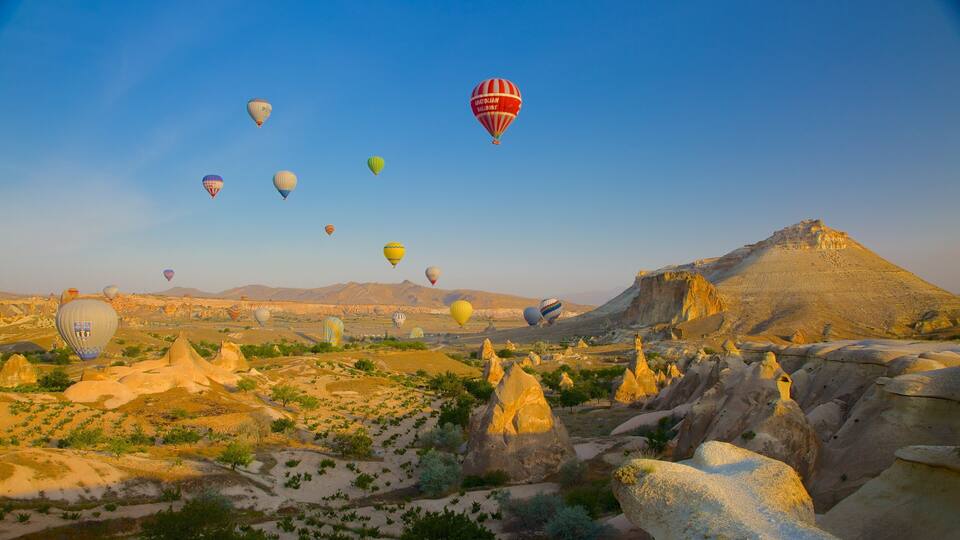 A landscape with rock formations and hot air balloons.