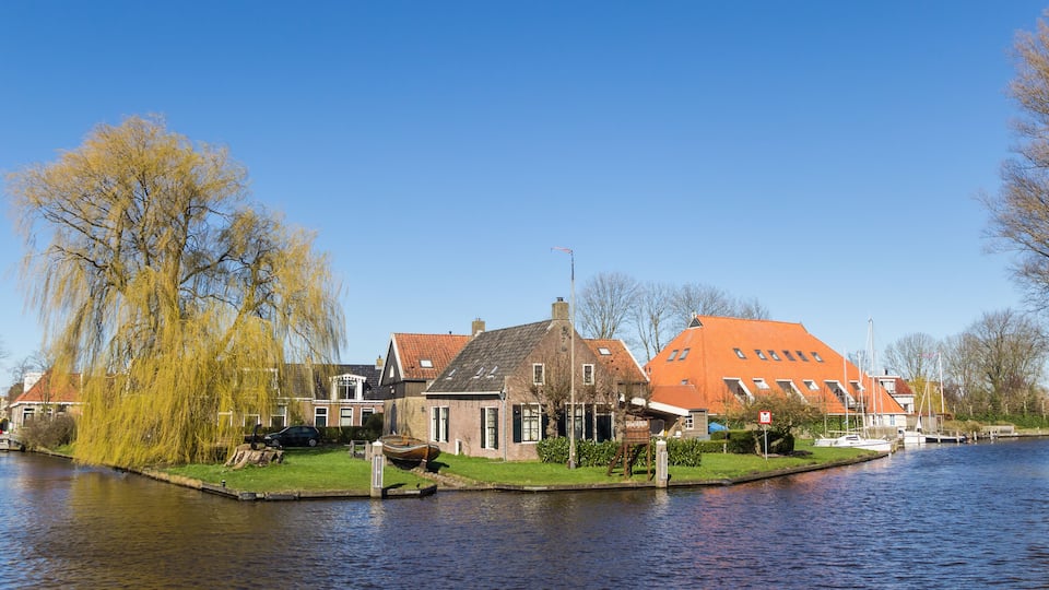 A canal with houses and a boat docked by the water.