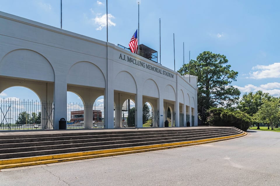 Le stade commémoratif A.J. McClung, avec un mât de drapeau, des marches et un ciel dégagé.