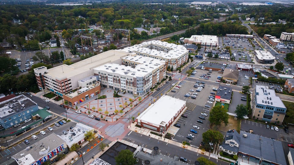 An aerial view of a city with a large parking lot, several buildings, and a river in the background.