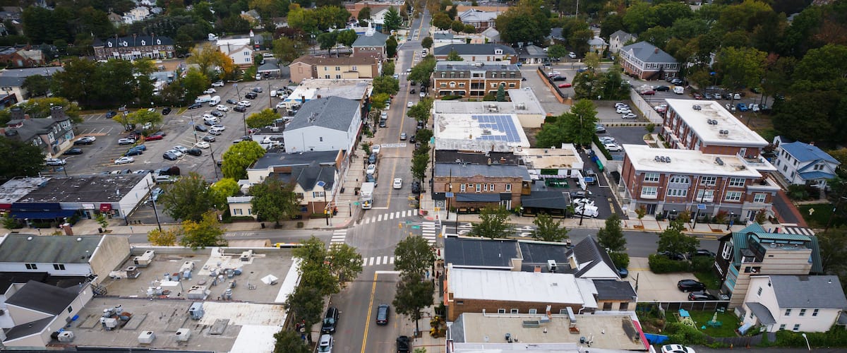 An aerial view of a town with a main street, buildings, and surrounding greenery.