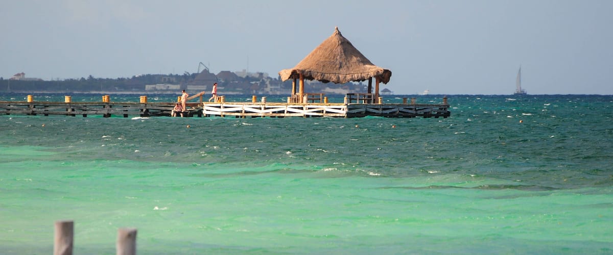 Rustic pier with thatched hut over turquoise waters in Puerto Morelos