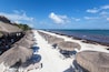 Een strand met rieten parasols en ligstoelen.