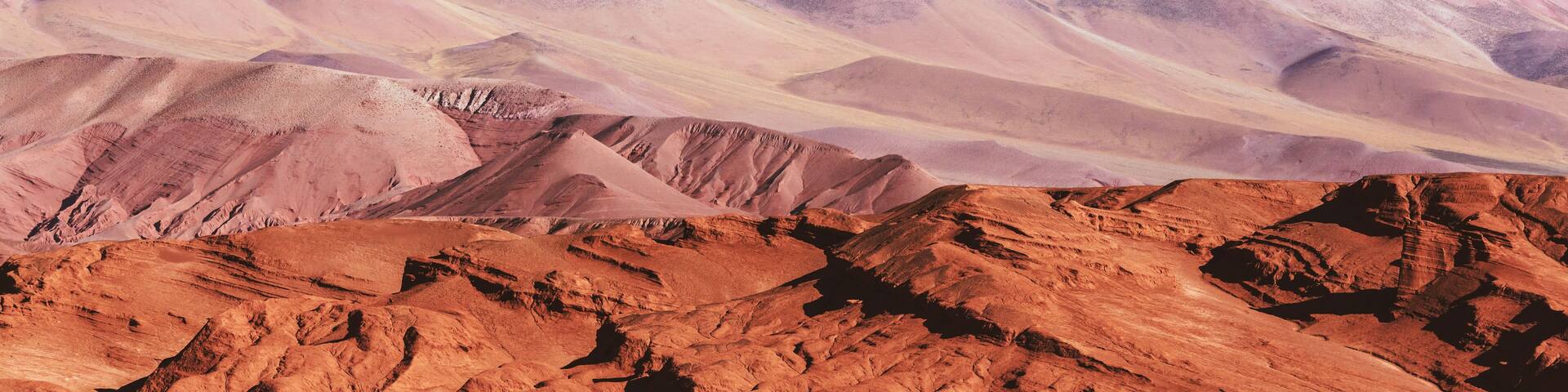 A rugged mountain range with layered rock formations and a clear sky.