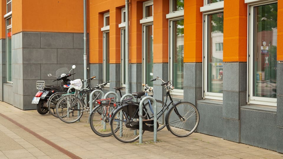 Une rangée de vélos est garée contre un bâtiment aux murs orange et gris.