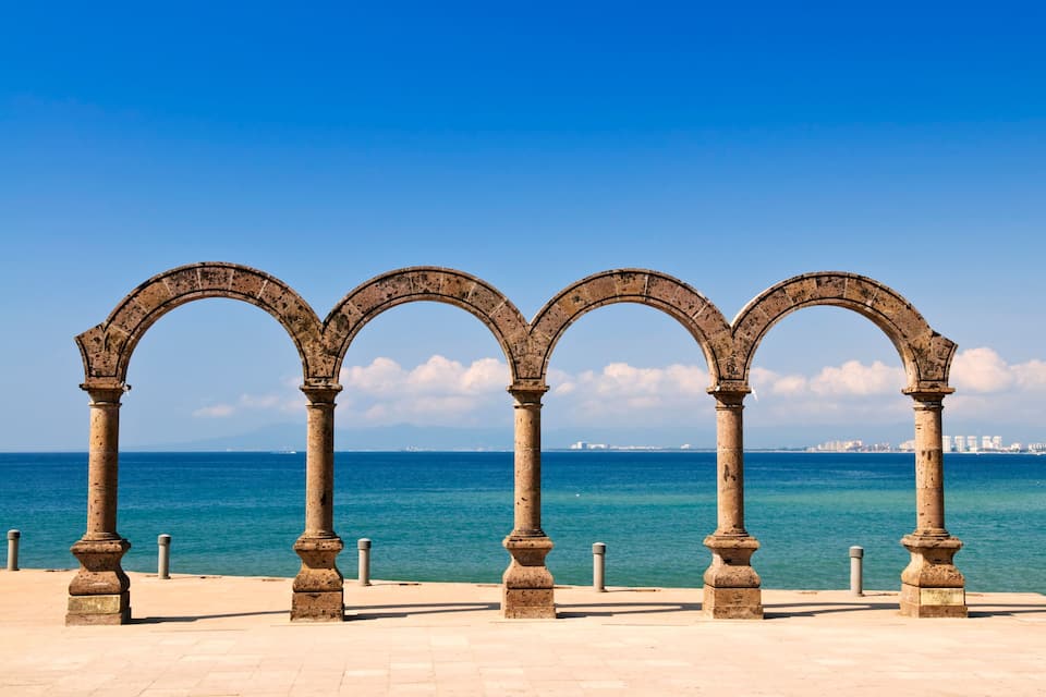 Un paseo marítimo con arcos de piedra y vista al mar.