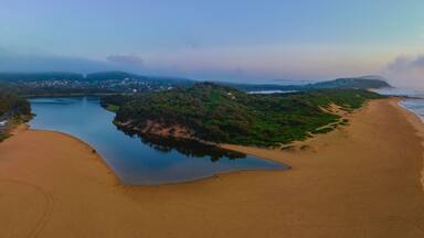 Summer sunrise panorama at the beach and lagoon with clouds and haze