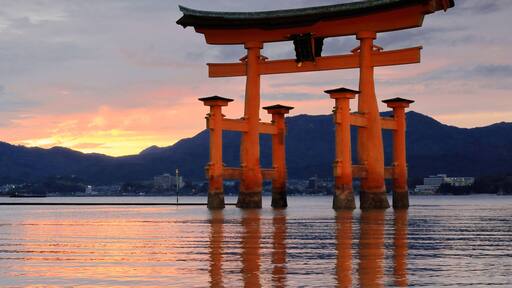 The c.500-600 years old-camphor tree-rotting resistant-vermilion lacquered main pillars+cedar tree sleeve pillars Itsukushima shrine Great Torii-gate at dusk-half tide. Miyajima-Hatsukaichi city-Japan