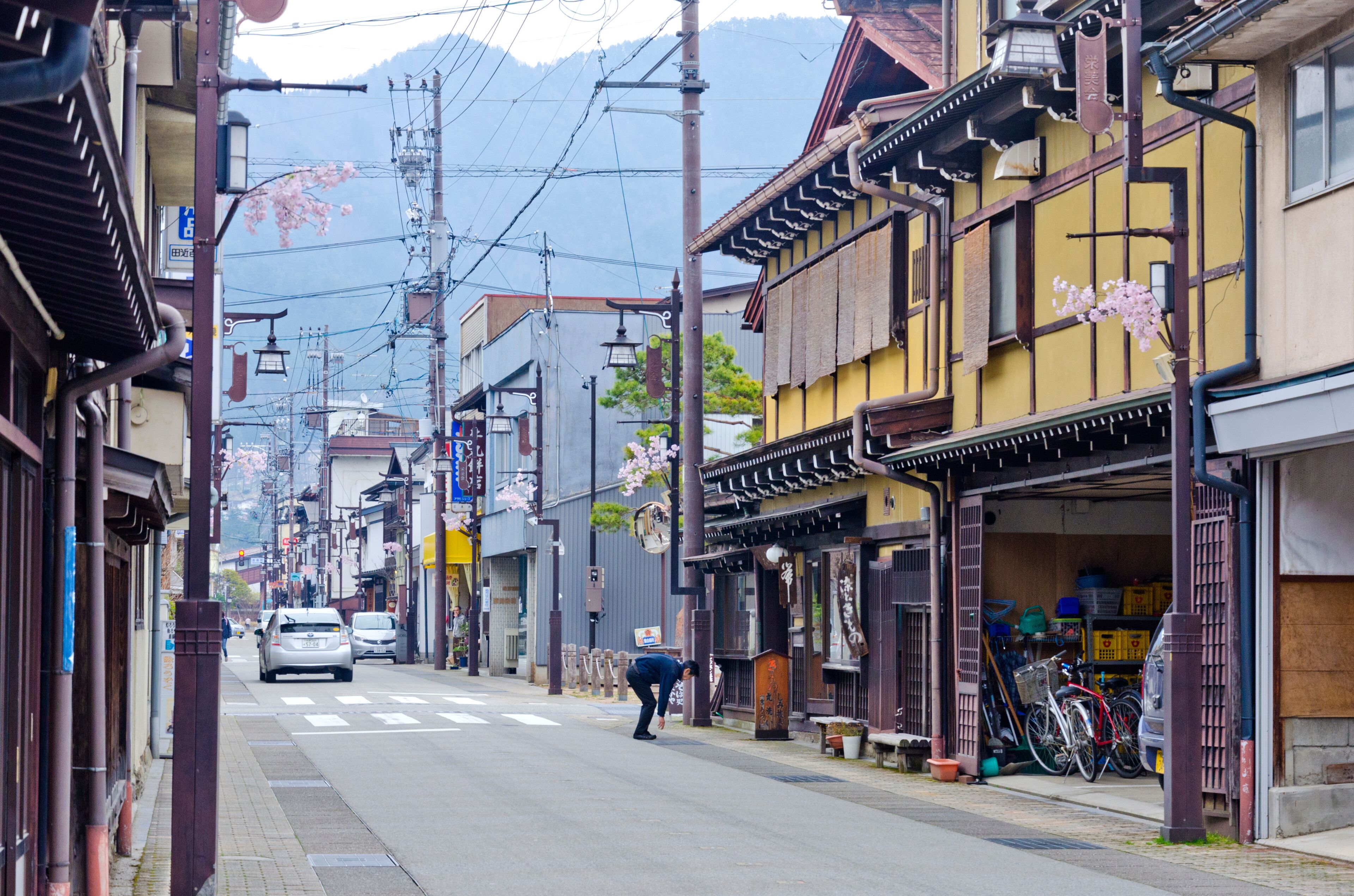 A street with traditional architecture, a parked bicycle, and a car.
