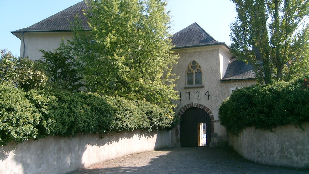 A historic building with a stone facade, a large arched entrance, and the number 1724 above it.