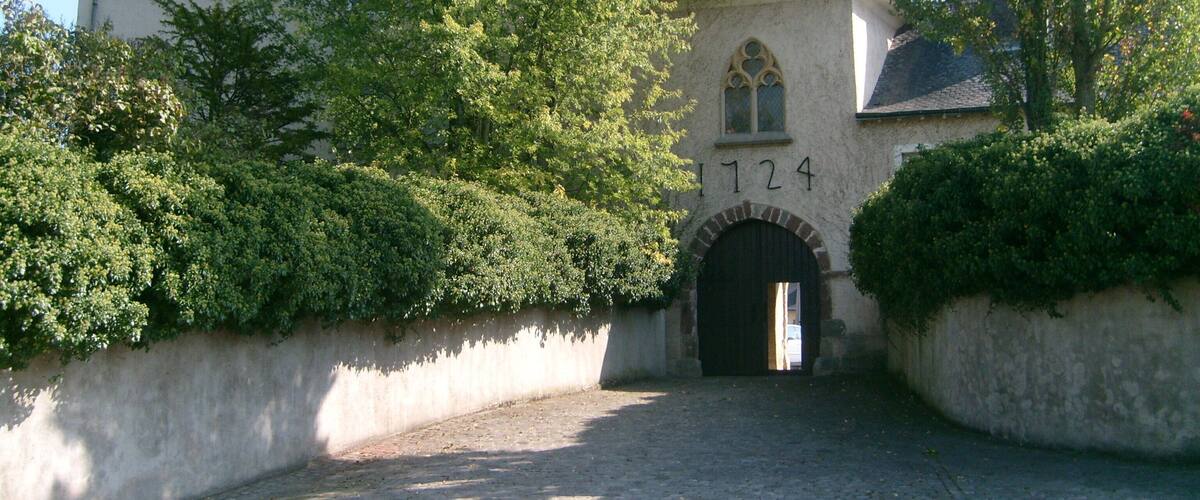 A historic building with a stone facade, a large arched entrance, and the number 1724 above it.