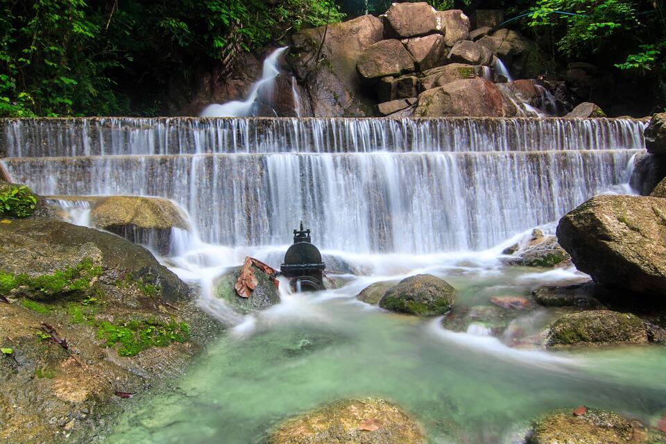 A waterfall cascading over rocks with a small structure in the middle.