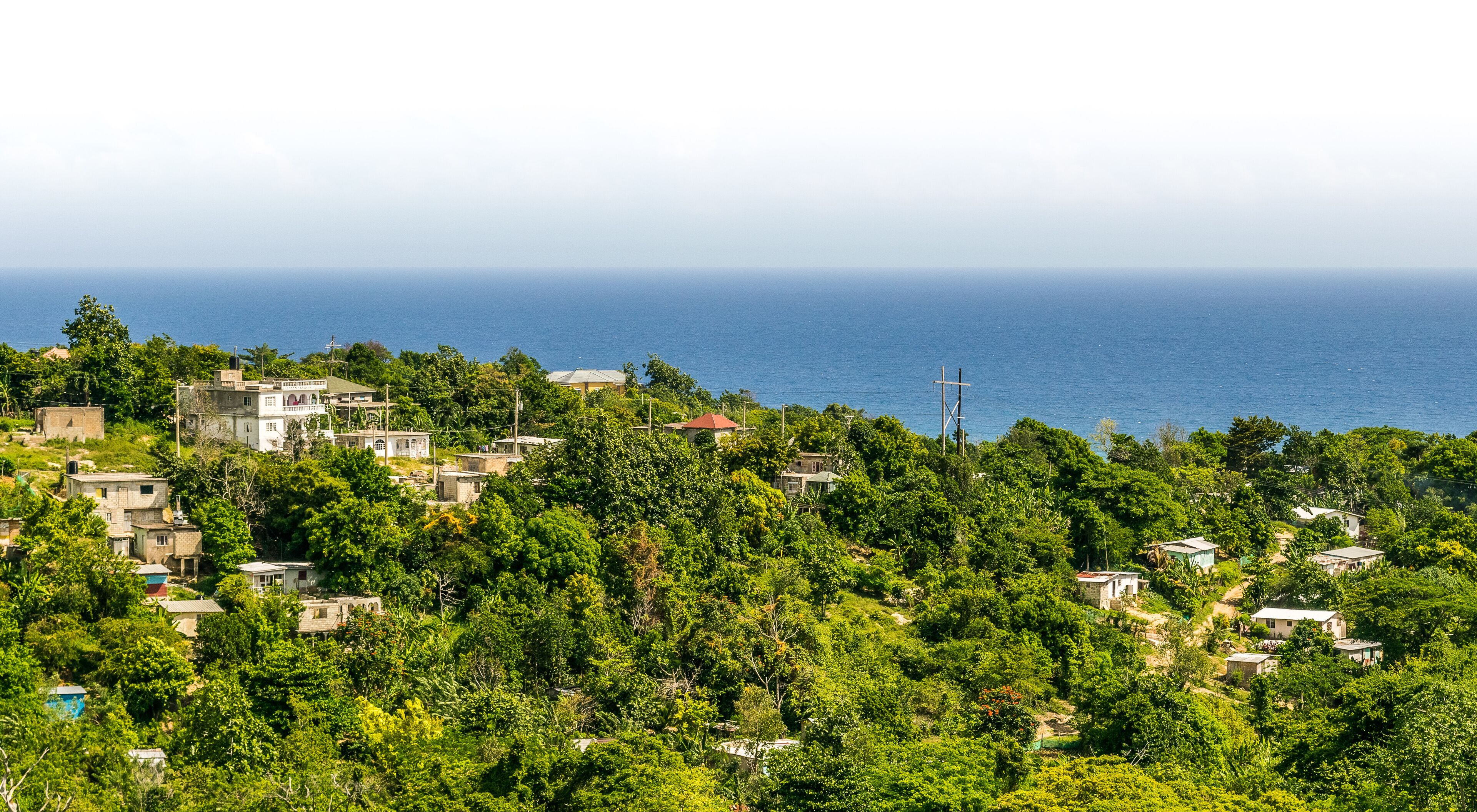 A coastal village with houses nestled among lush greenery, overlooking the sea.