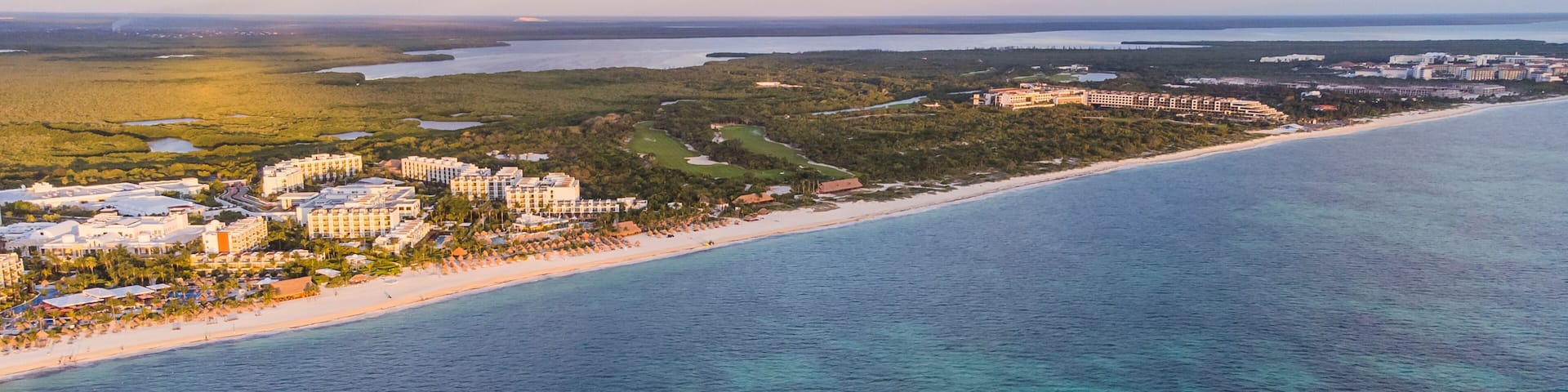 A coastal resort area with beachfront hotels, a sandy beach, and a large body of water.