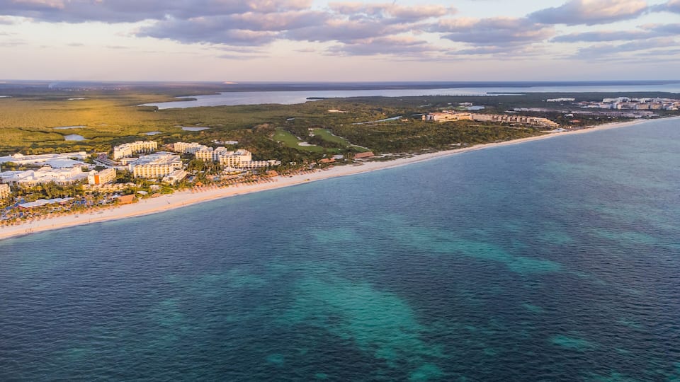 A coastal resort area with beachfront hotels, a sandy beach, and a large body of water.