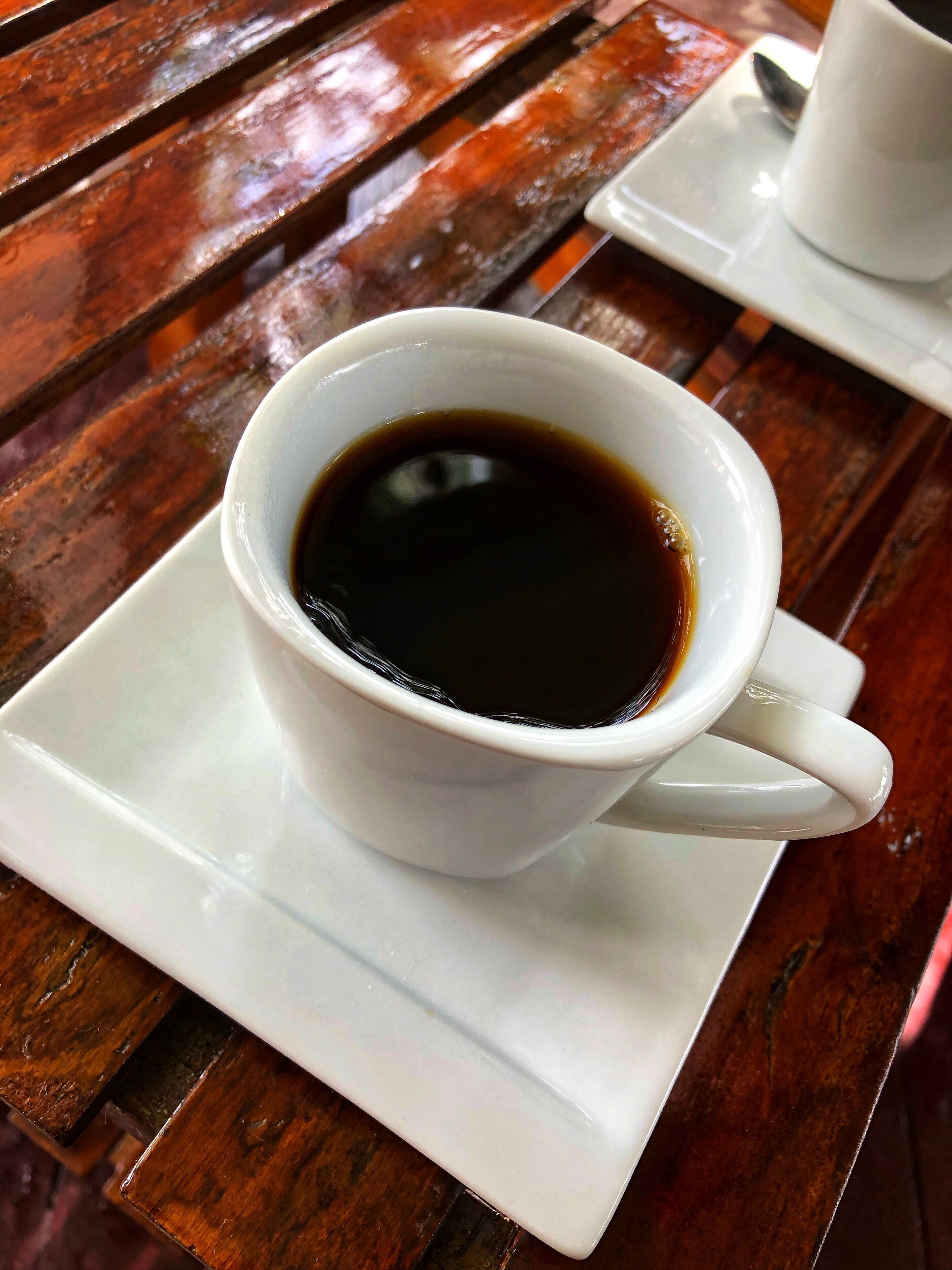 Una taza blanca de café sobre un plato pequeño blanco.