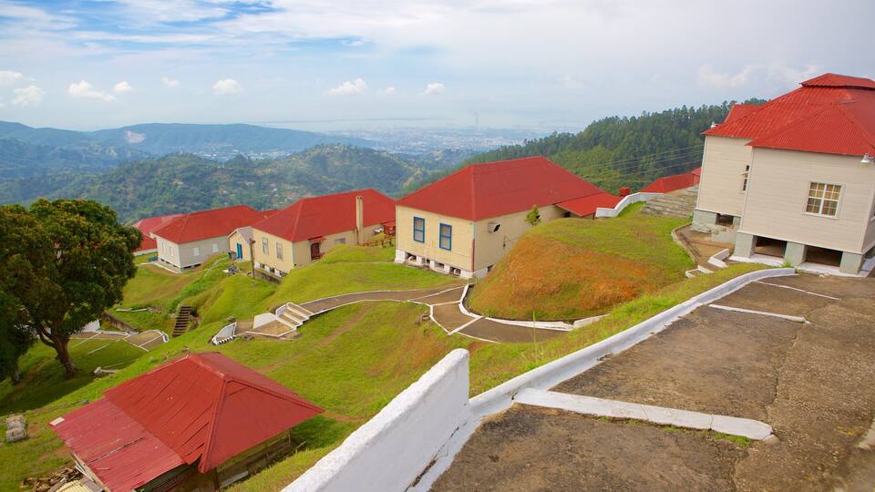 A hillside village with red-roofed houses and a view of distant mountains.