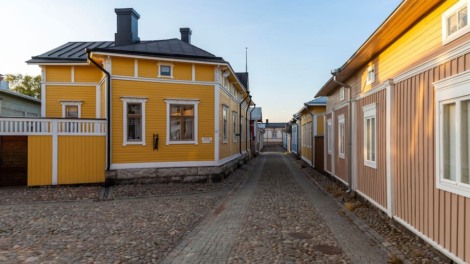 Una calle adoquinada flanqueada por casas de madera amarillas y marrones.