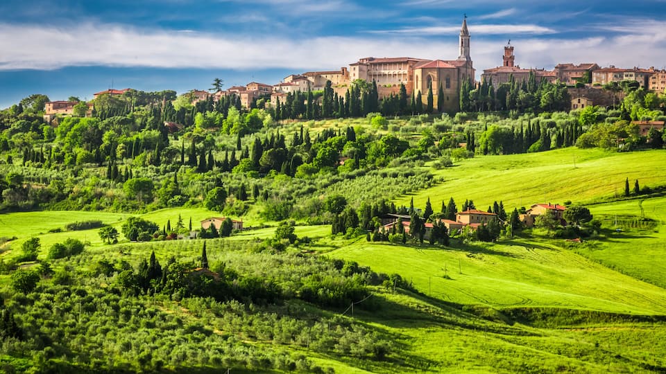 Rolling green hills, a historic town with red-roofed buildings, and a prominent church tower.