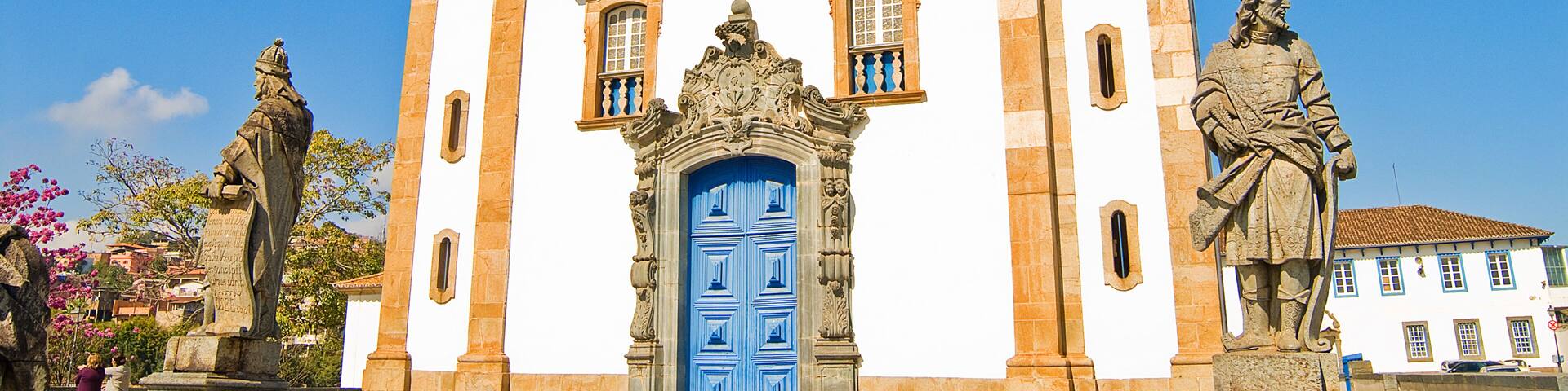 A historic church with a blue door, two bell towers, and statues.