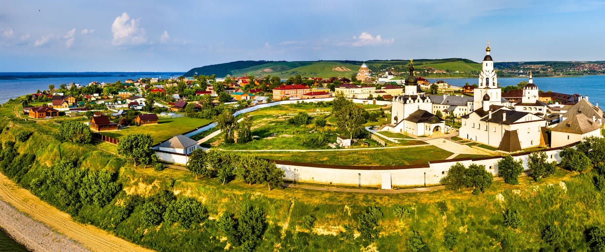 A coastal town with a prominent church, a river, and surrounding greenery.