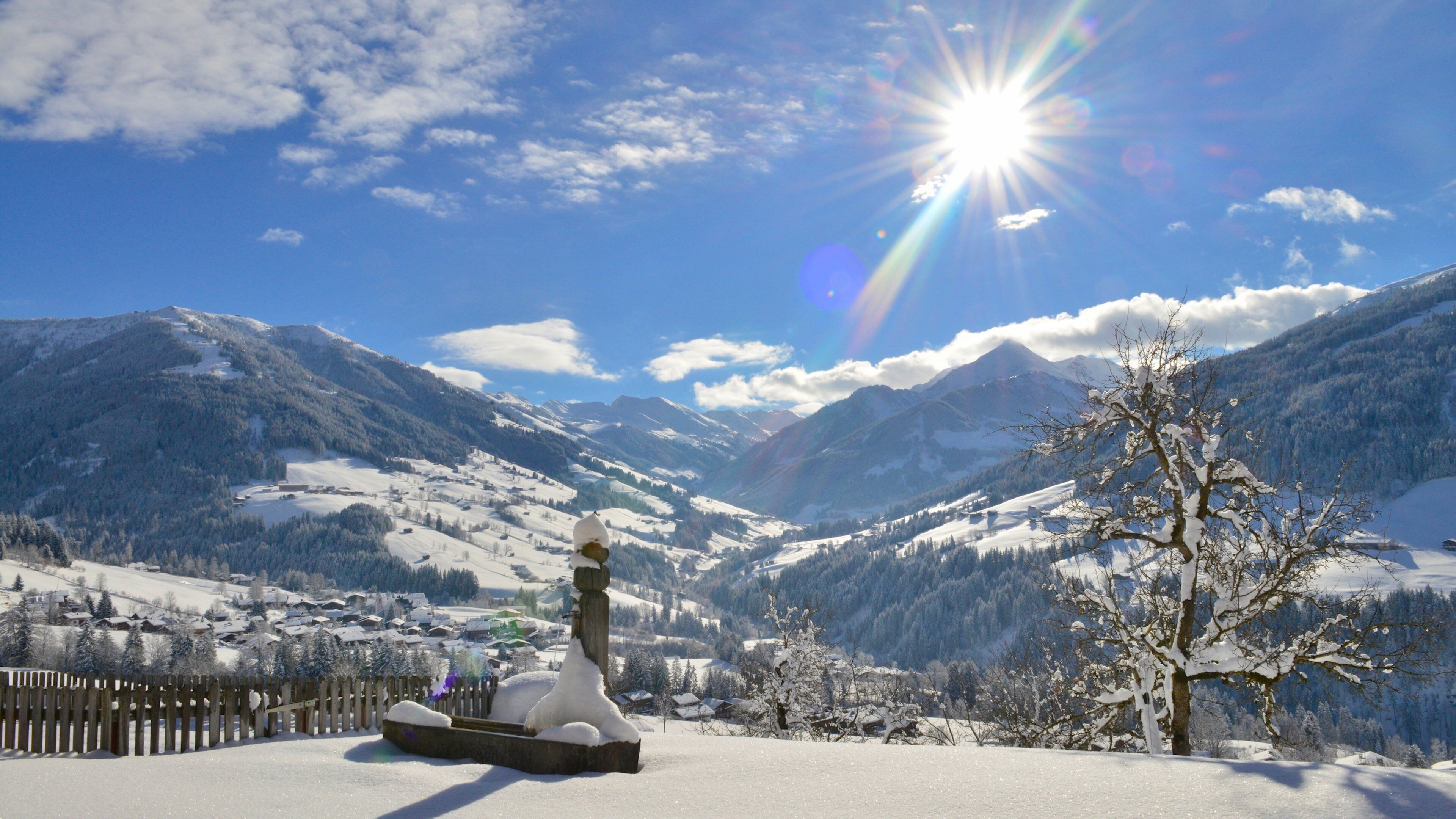 A snow-covered mountain landscape with a wooden fence and a snow sculpture.
