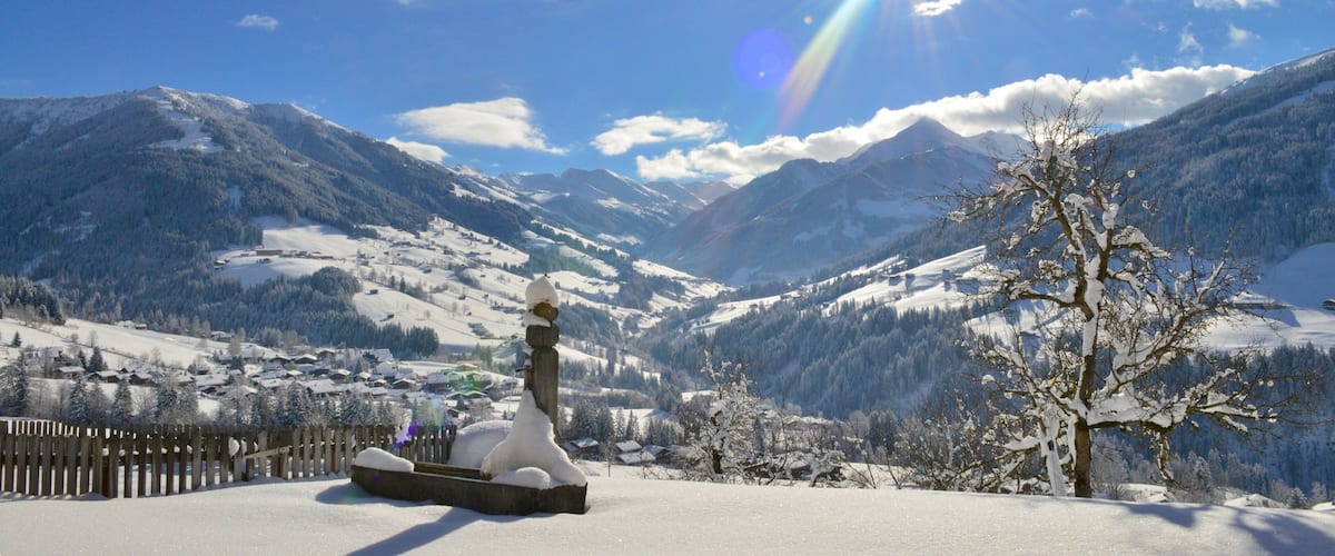 A snow-covered mountain landscape with a wooden fence and a snow sculpture.