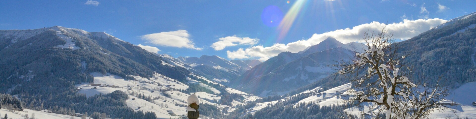 A snow-covered mountain landscape with a wooden fence and a snow sculpture.