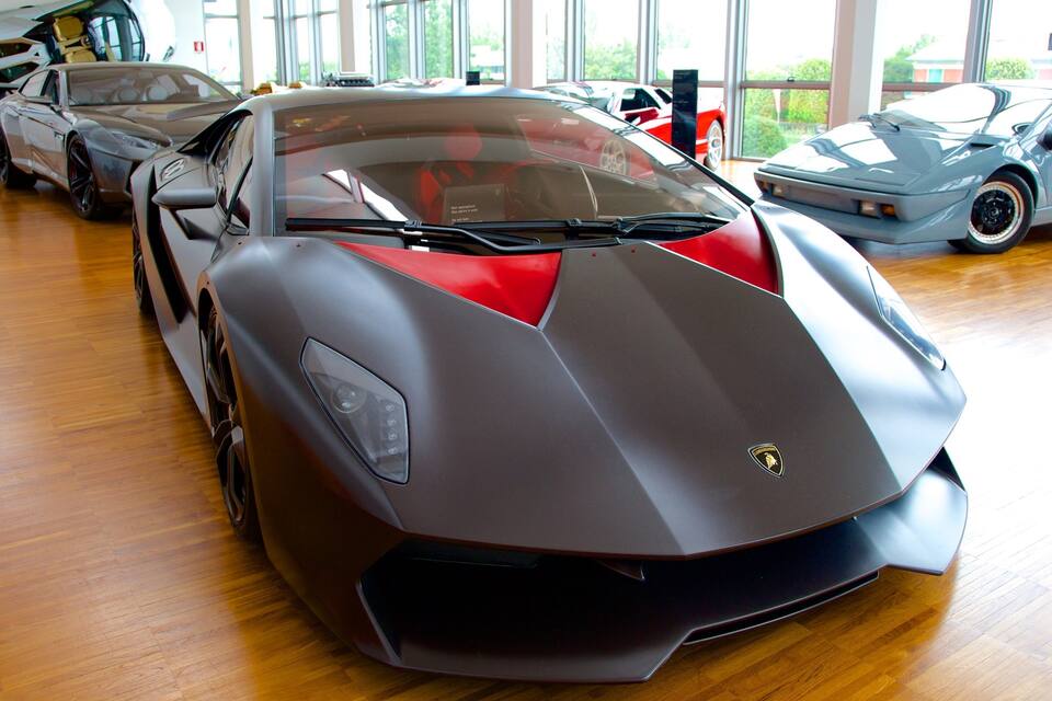 A luxury car showroom with a sleek, modern car in the foreground.