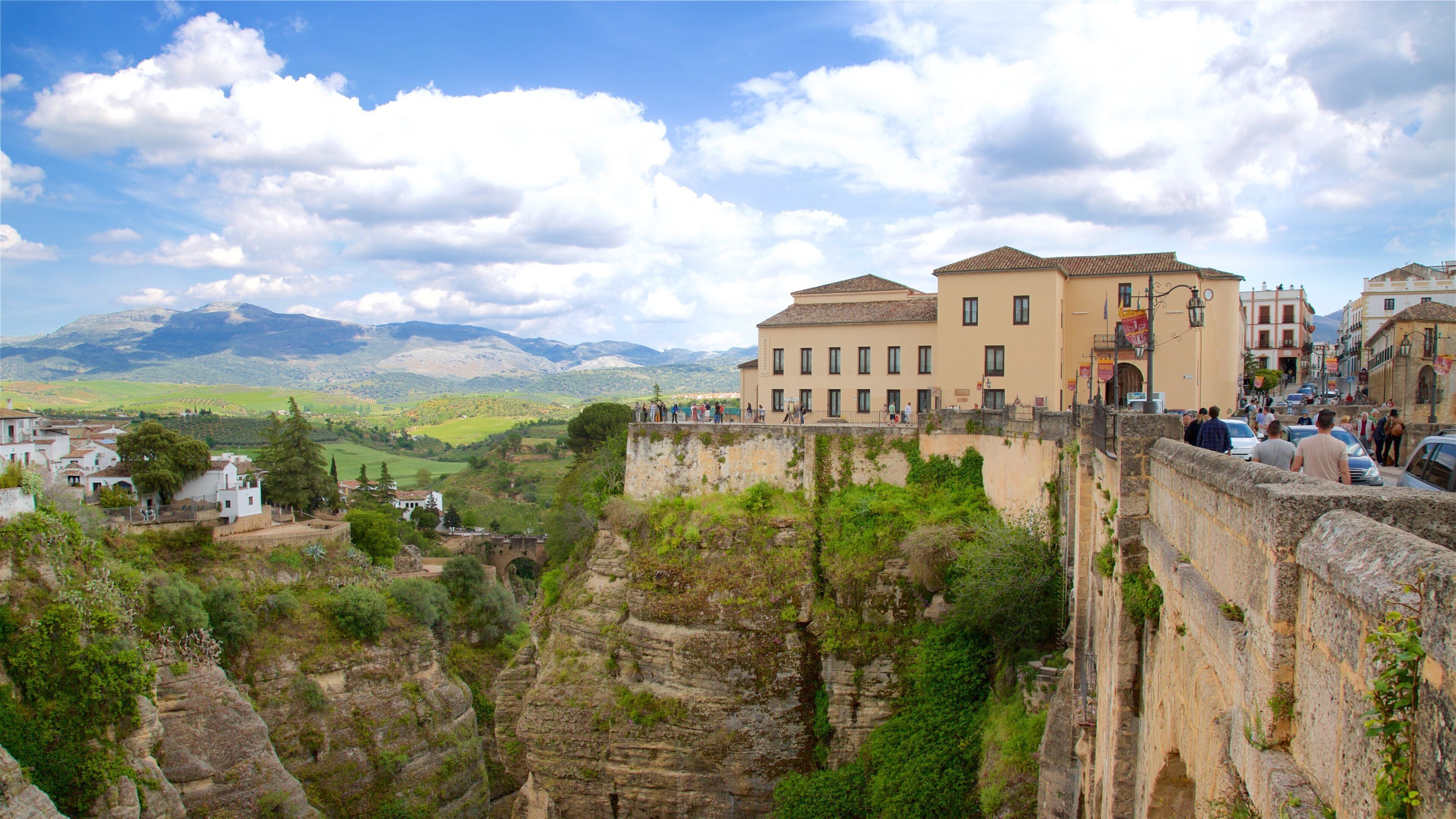 A historic stone wall with a view of a town and mountains in the background.