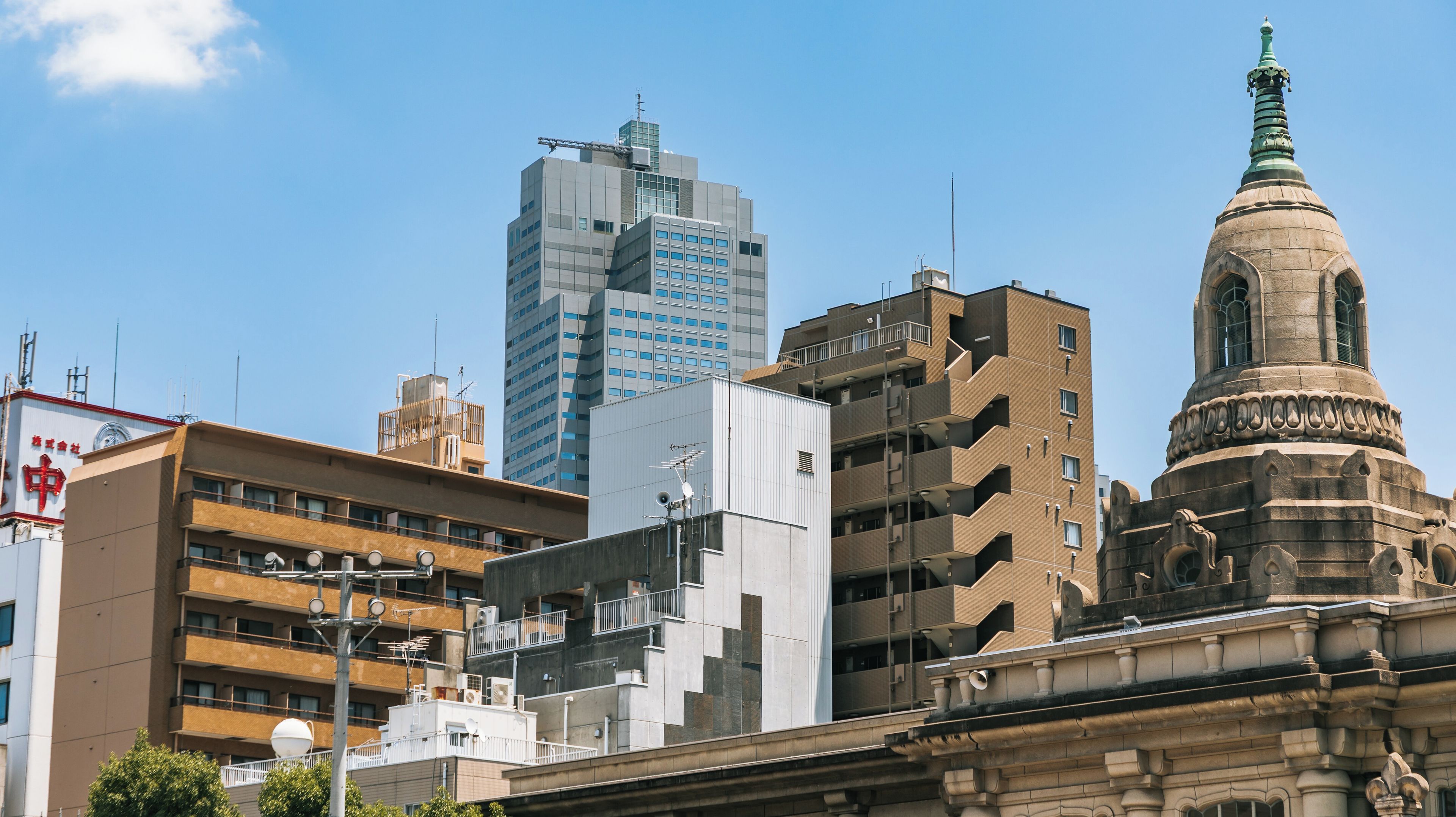 Een stadsgezicht met moderne en historische gebouwen, waaronder een opvallende toren met een spits.