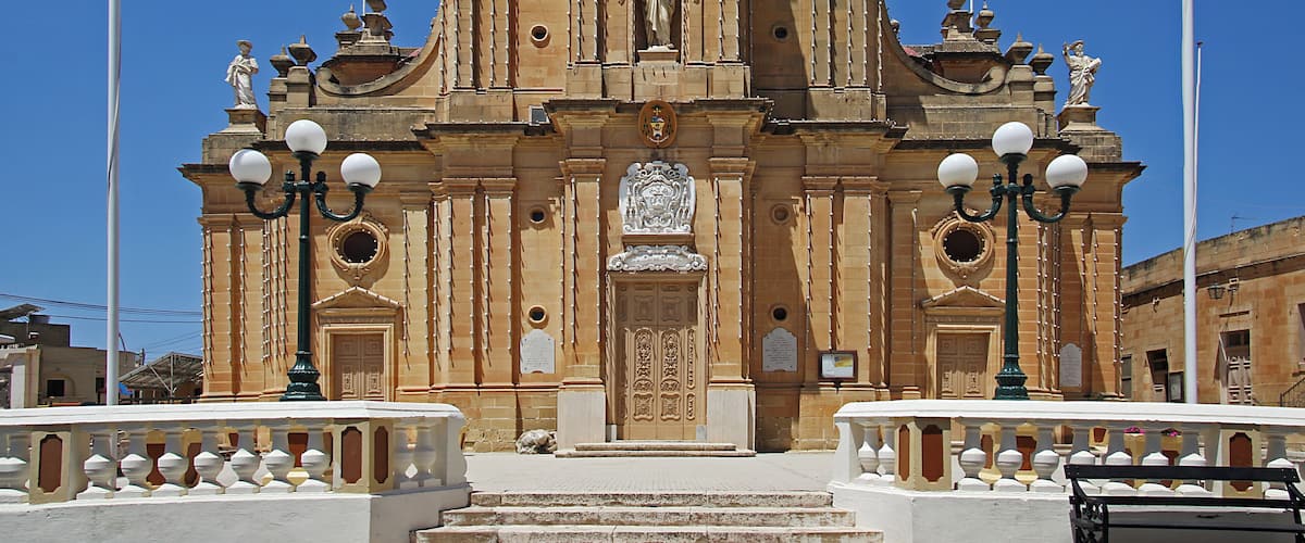 A historic church with a bell tower, ornate facade, and statues.