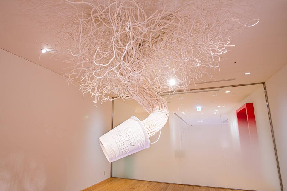 A modern art installation with a hanging structure made of intertwined white materials.