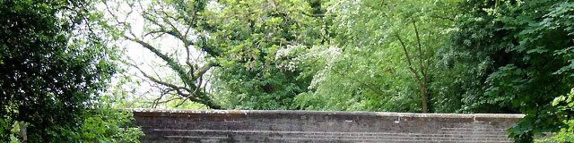 A narrowboat on a canal under a stone bridge.