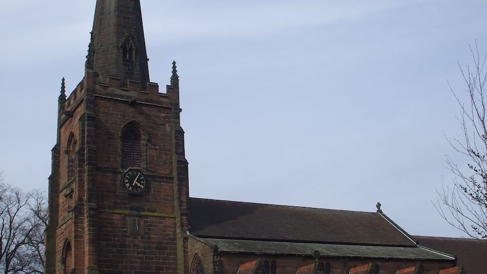Een kerk met een hoge spits en een klok.