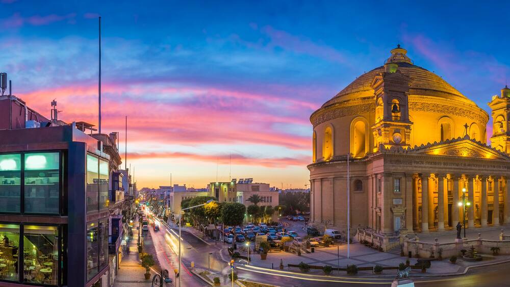 Malta - Panoramic skyline view of the famous Mosta Dome and maltese houses with amazing colorful sky at sunset