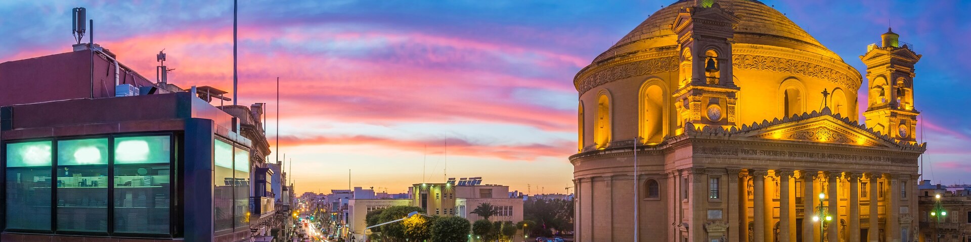 Malta - Panoramic skyline view of the famous Mosta Dome and maltese houses with amazing colorful sky at sunset