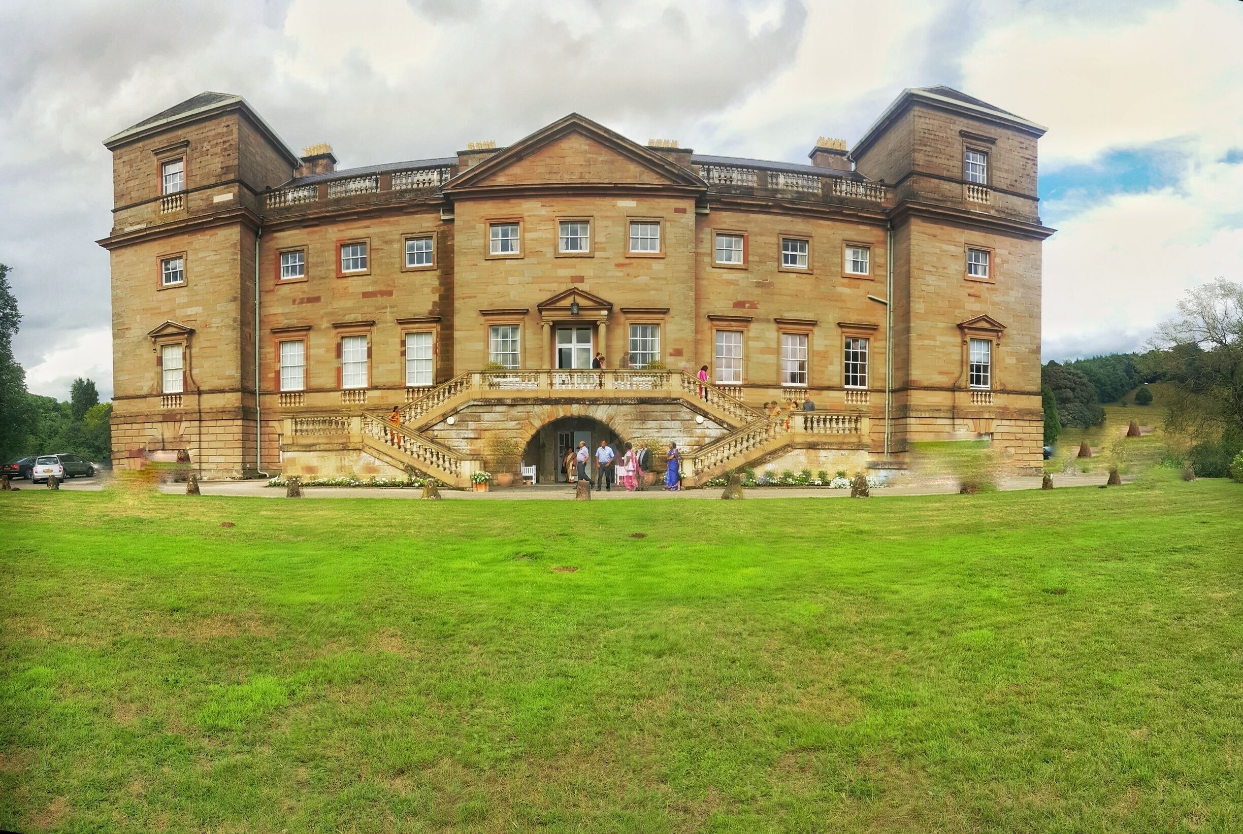 A large, historic stone building with a central entrance and a staircase leading up to it.