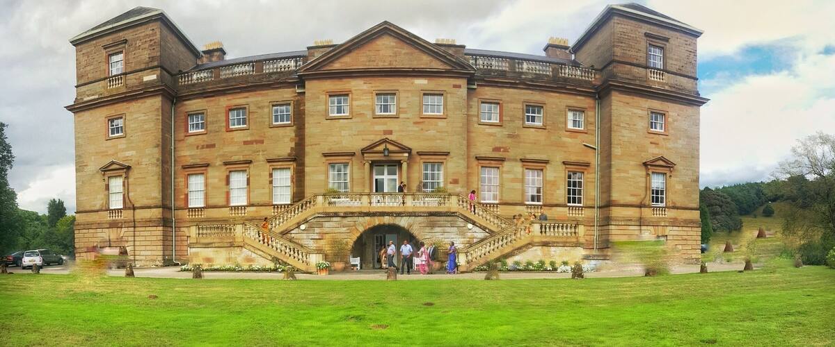 A large, historic stone building with a central entrance and a staircase leading up to it.