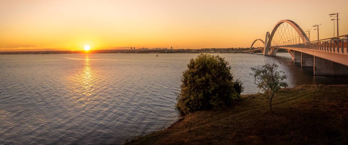 A sunset over a river with a bridge.