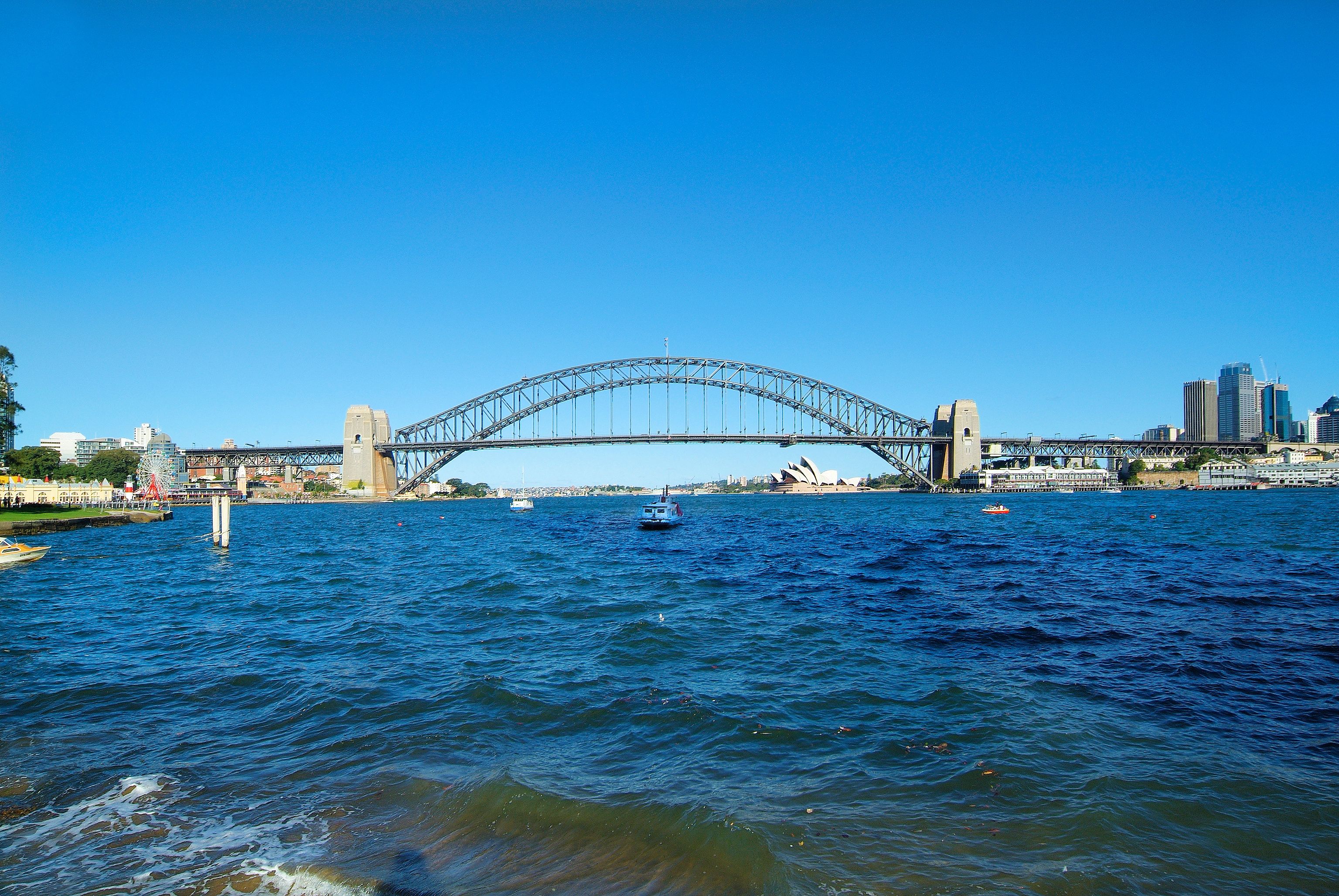 A large bridge spanning a body of water with a city skyline in the background.