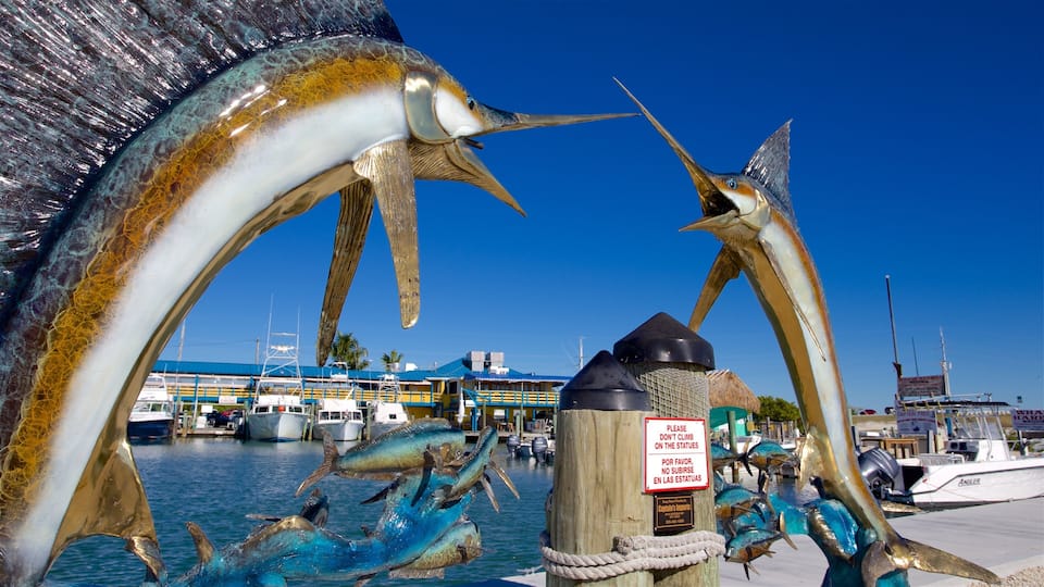 A pier with large fish sculptures and boats in the background.