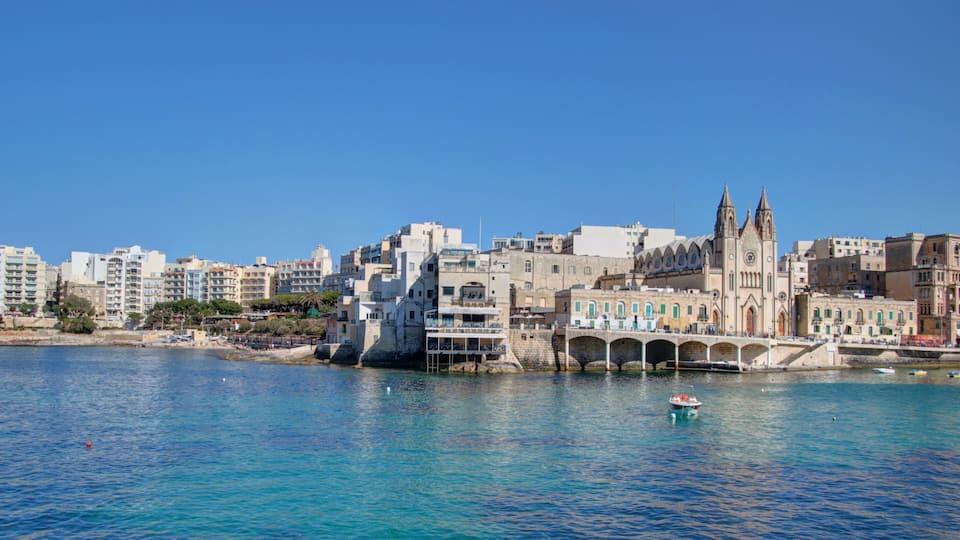 A coastal cityscape with a prominent church and a bridge over the water.