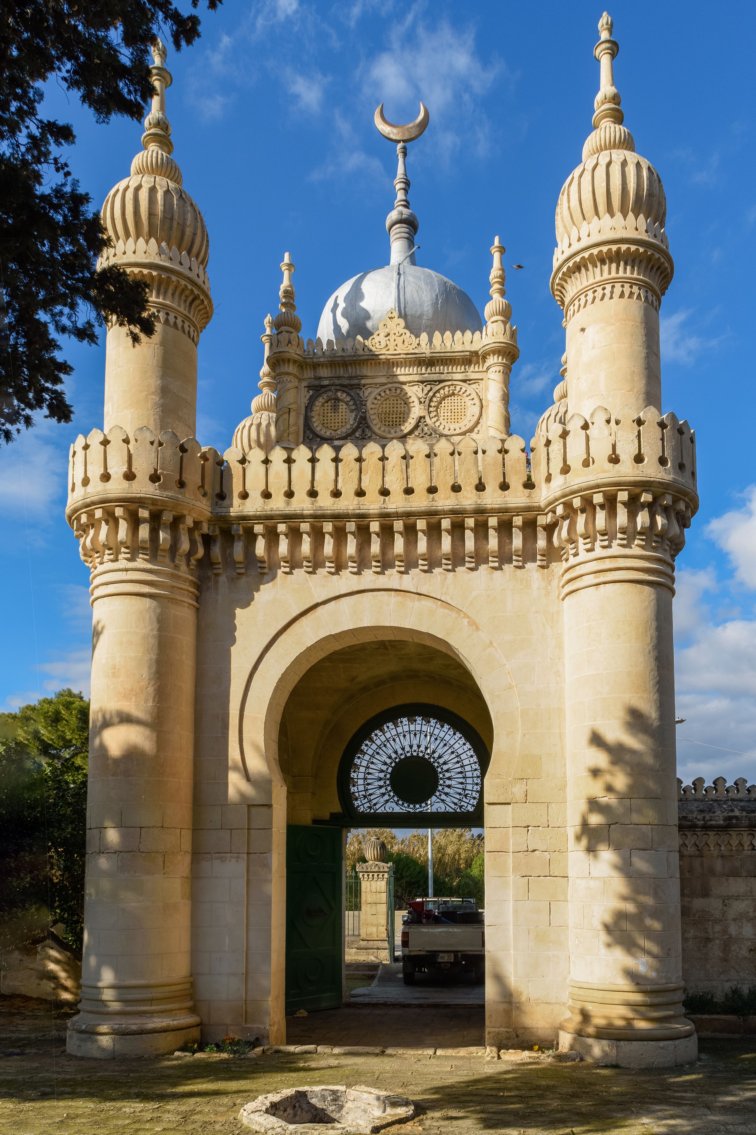 A historic gate with a crescent moon on top, intricate carvings, and a large archway.