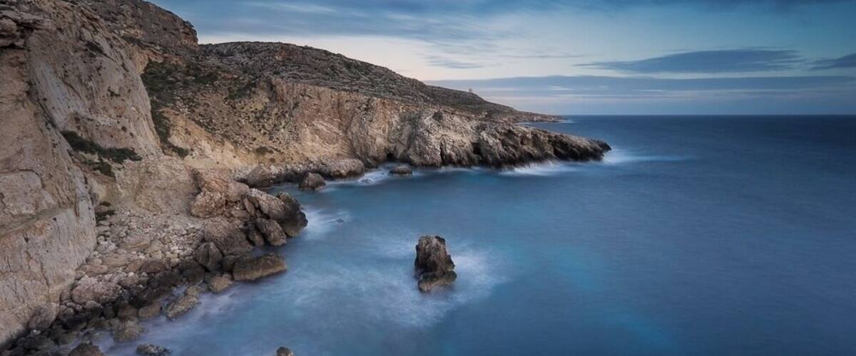 A coastal landscape with rocky cliffs and calm sea.